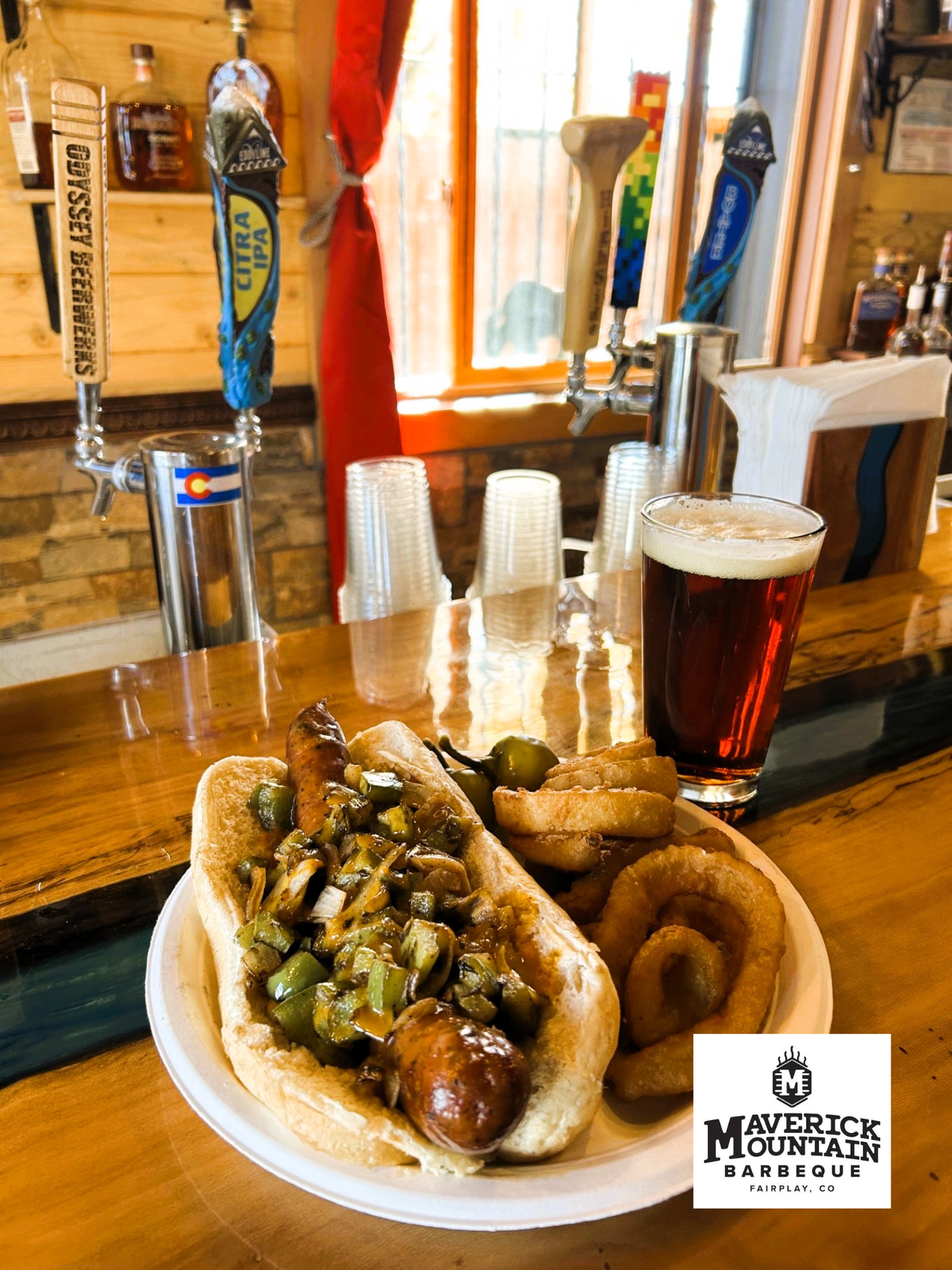 Maverick's sausage with peppers, onions, onion rings, and a draft beer at The Den